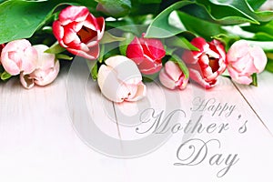 happy mother's day text sign on pink tulips on white rustic wooden background. greeting card concept. sensual tender women image.