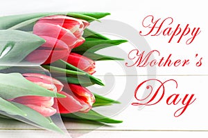 happy mother's day text sign on pink tulips on white rustic wooden background. greeting card concept. sensual tender women image.