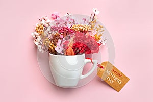 Happy Mother\'s Day. White cup of coffee with various flowers and brown sale tag with the text Happy Mothers day