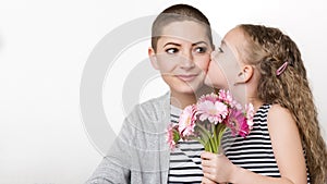 Happy Mother`s Day, Women`s day or Birthday background. Cute little girl giving mom, cancer survivor, bouquet of gerbera daisies.