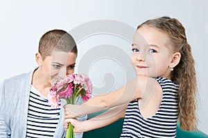 Happy Mother`s Day, Women`s day or Birthday background. Cute little girl giving mom bouquet of pink gerbera daisies.