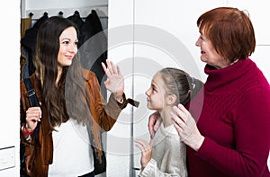 Happy mother saying goodbye to daughter with grandma