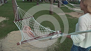 Happy mother shakes her daughters in hammock slow motion stock footage video