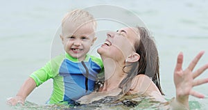 A happy mother with a small child is having fun in the sea.