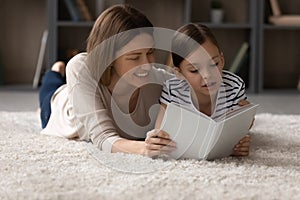 Happy mother and small daughter reading book together