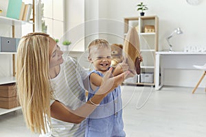 Happy mother with smiling baby boy playing together with wooden rocket at home