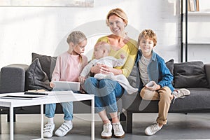 happy mother smiling at camera while sitting on couch