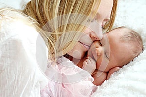 Happy Mother Snuggling Newborn Baby in Bed