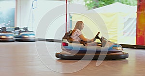Happy mother with son drive bumper dodge car in amusement park