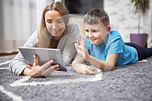 Happy mother and son greeting online looking at web camera using tablet pc