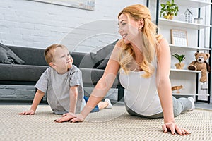 Happy mother and son practicing yoga in modern living