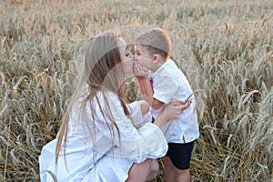 Happy mother and son are running through a wheat field.