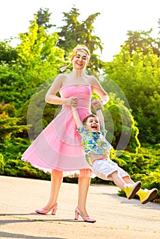 Happy Mother and son spinning in summer park
