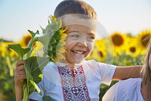 Happy mother and son in Ukrainian clothes - embroiderers in a field of sunflowers