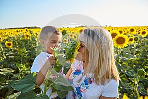 Happy mother and son in Ukrainian clothes - embroiderers in a field of sunflowers