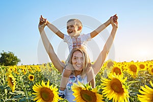 Happy mother and son in Ukrainian clothes - embroiderers in a field of sunflowers
