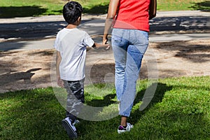 Happy mother and son walking together outdoors in a park.