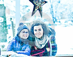 Happy mother  and son whispers  sitting outdoor at winter christmas time.  Family fun. Christmas card