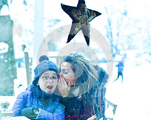 Happy mother  and son whispers  sitting outdoor at winter christmas time.  Family fun. Christmas card