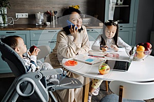 Happy mother talking on cellphone while spending time with her children