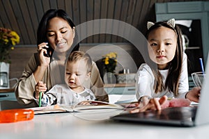 Happy mother talking on cellphone while spending time with her children