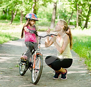 Happy mother talking with her daughter smiling, which teaches to biking