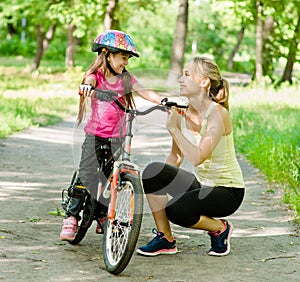 Happy mother talking with her â€‹â€‹daughter smiling, which teaching biking