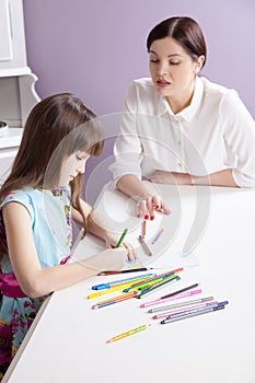 Happy mother teach her daughter to paint.