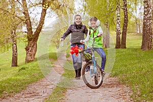 Happy mother teaches his daughter to ride a bike. A mother is glad to successes of daughter