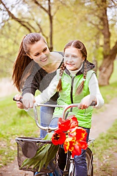 Happy mother teaches his daughter to ride a bike. A mother is glad to successes of daughter