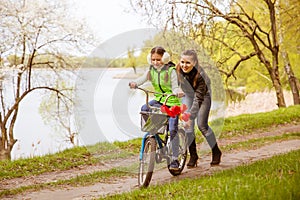 Happy mother teaches his daughter to ride a bike. Mother holds daughter from falling