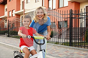 Happy mother teaching her son to ride bicycle