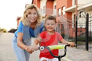 Happy mother teaching her son to ride  in city