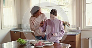 Happy mother teaching teenage child daughter cooking vegetarian food.