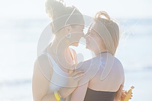 happy mother and teenage daughter at beach applying sunscreen