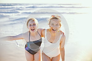 happy mother and teenage daughter at beach having fun time