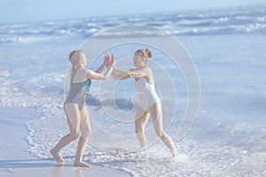 happy mother and teenage daughter at beach having fun time