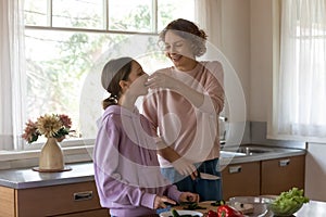 Happy mother and teenage daughter cooking in modern kitchen together