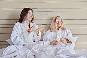 Happy mother and teenage daughter drinking coffee and talking