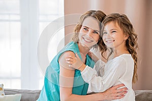 Happy mother and teenage daughter hugging at home