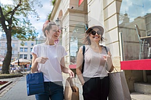 Happy mother and teenage daughter walking together with shopping bags