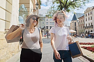 Happy mother and teenage daughter walking together with shopping bags