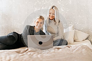 Happy mother with teenager daughter browsing online with application, watching video together, online shopping