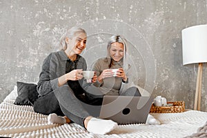 Happy mother with teenager daughter browsing online with application, watching video together, online shopping