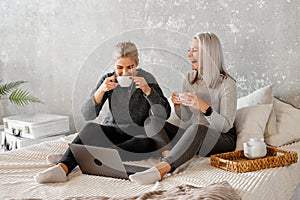 Happy mother with teenager daughter browsing online with application, watching video together,or zoom conversation