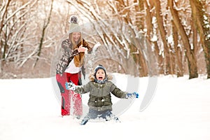 Happy mother throwing snow on her son. Family on a winter walk at nature. Happy winter holidays. Healthy lifestyle