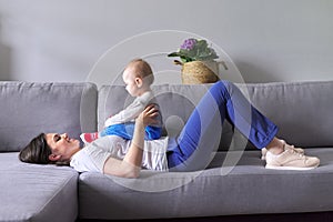 Happy mother with toddler son at home. Laughing woman playing with baby