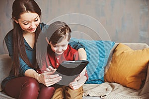 happy mother and toddler son using tablet at home. Family playing computer or searching internet
