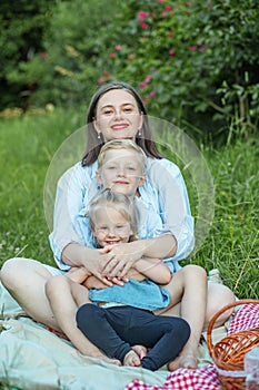 Happy mother and two children have picnic in summer park. Family, vacation and summer season concept