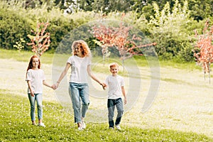 happy mother with two children holding hands and walking